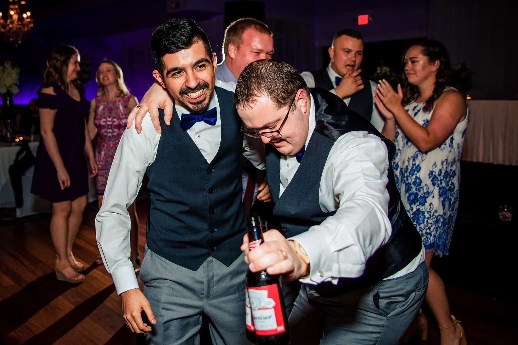 A group of men dancing on the dance floor at a wedding.