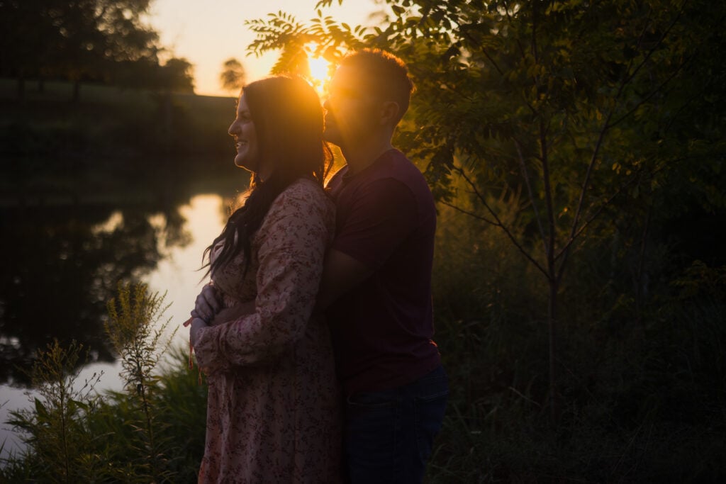 Engagement Couple Embracing At A Lake During Sunset In Harrodsburg.
