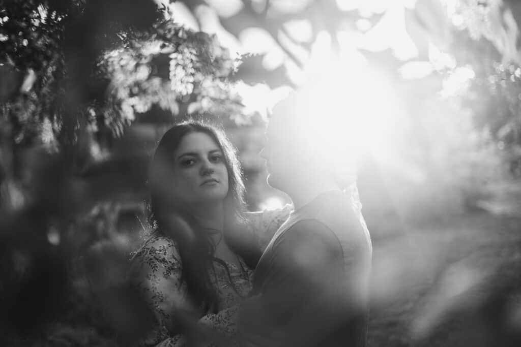 An Engagement Photo Of A Couple Embracing Under A Tree.