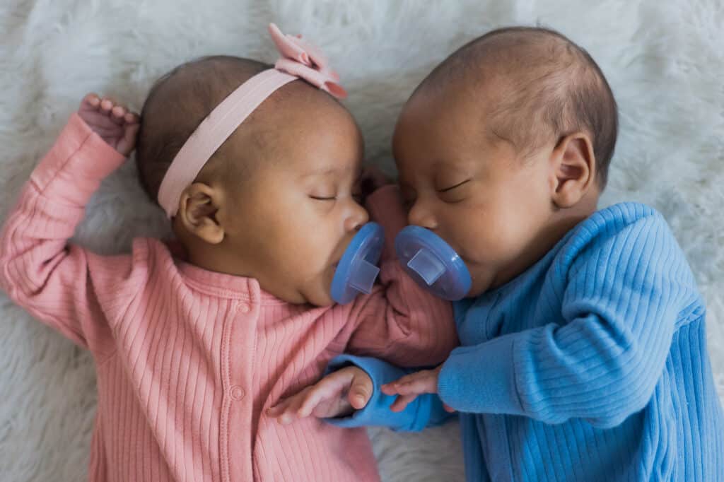 Adorable newborn twin photography session in Lexington captures two peacefully sleeping baby twins on a soft white blanket.