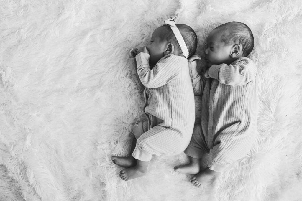 Captivating black and white photo capturing newborn twin photography in Lexington. The adorable twins are peacefully laying on a soft blanket, creating a precious moment frozen in time.