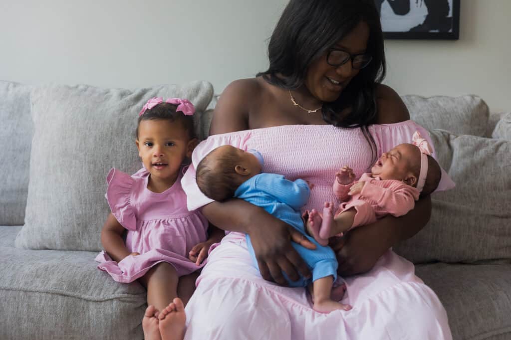 A woman holding her newborn twins on a couch during a beautiful Lexington photoshoot.