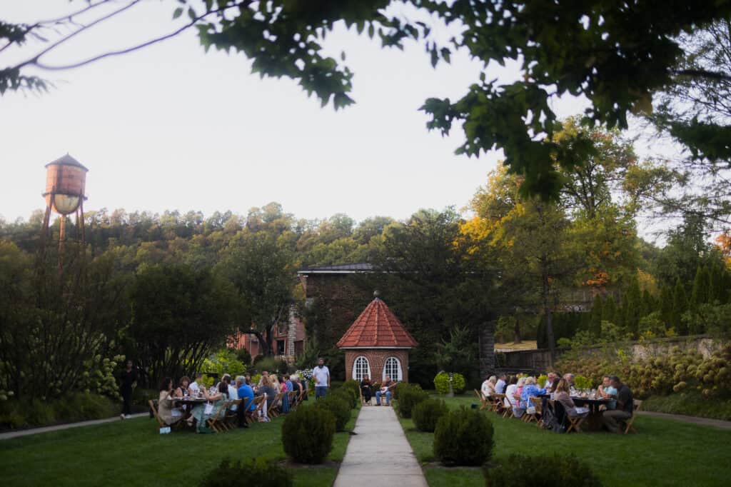 A group of people are sitting at a table in a beautiful garden while enjoying an exceptional Kentucky event.