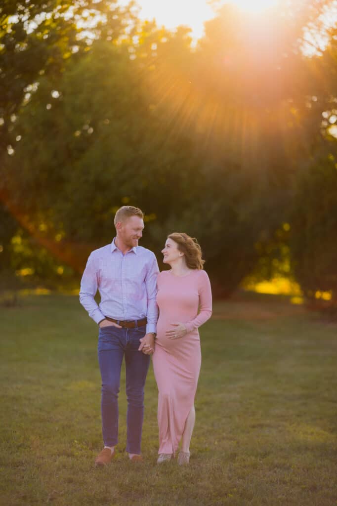 Lexington KY Maternity Photographer captures couple standing in a field at sunset during their session.
