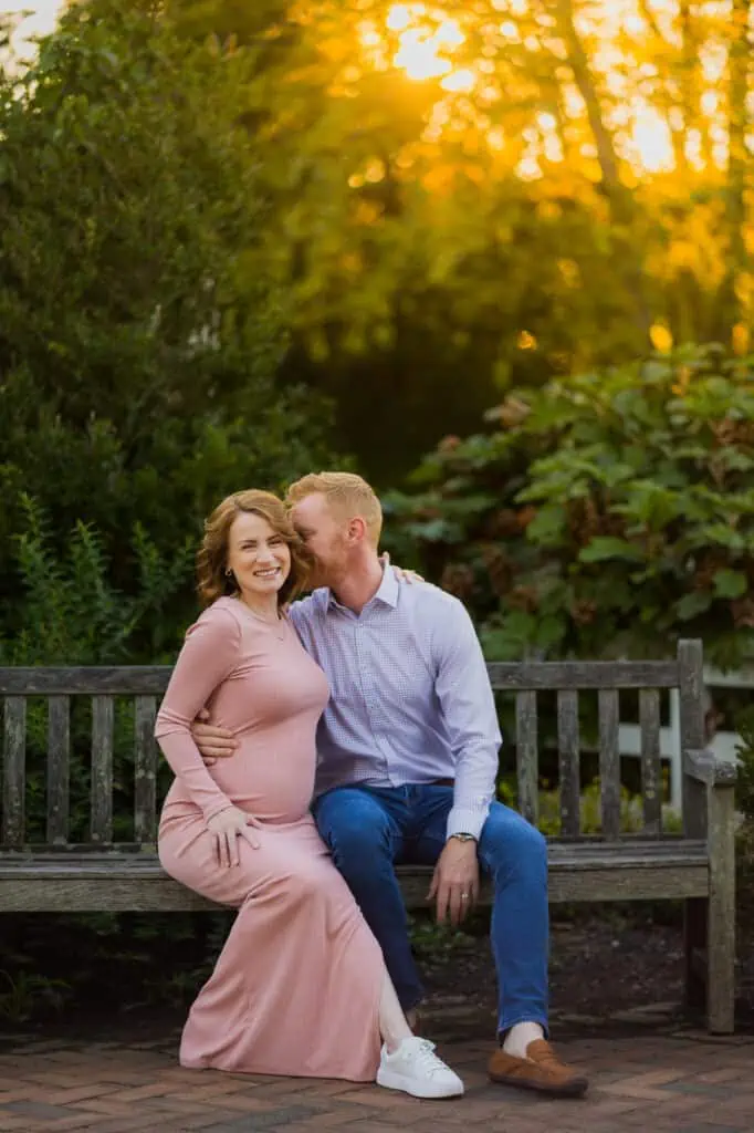 A couple sits on a bench at sunset during their maternity session with a Lexington KY Maternity Photographer.