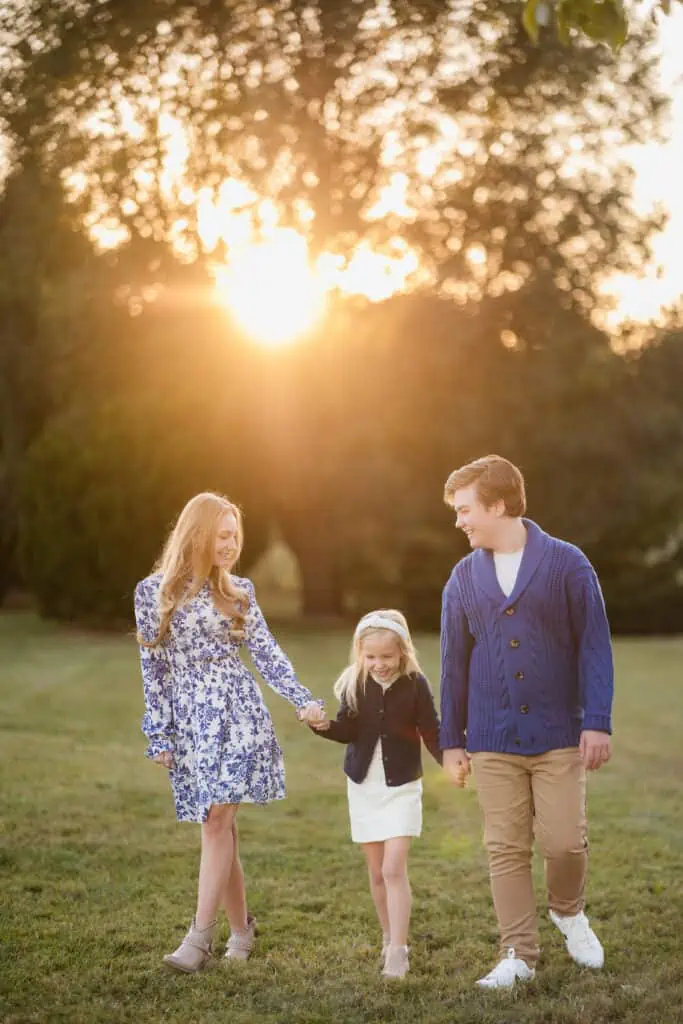 A LGBTQ+ family holding hands in a field at sunset, captured by a photographer in Lexington, Ky.