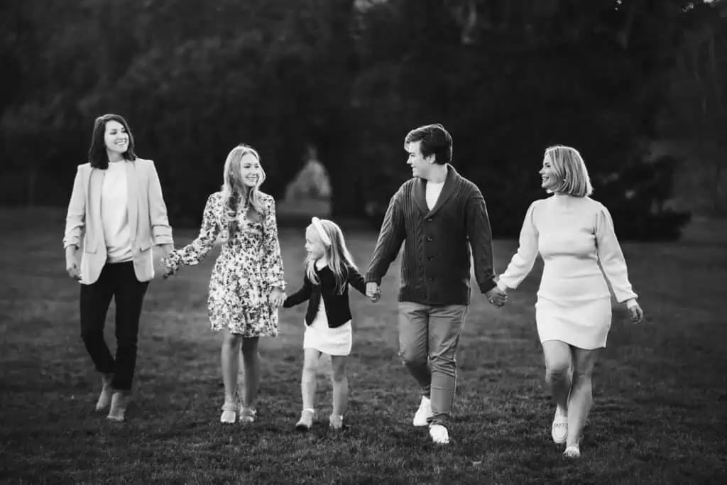A black and white photo by an LGBTQ+ family photographer in Lexington, Ky, capturing a family holding hands in a park.