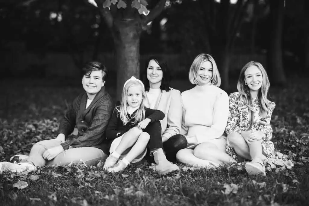 A black and white photo of an LGBTQ+ family sitting under a tree.